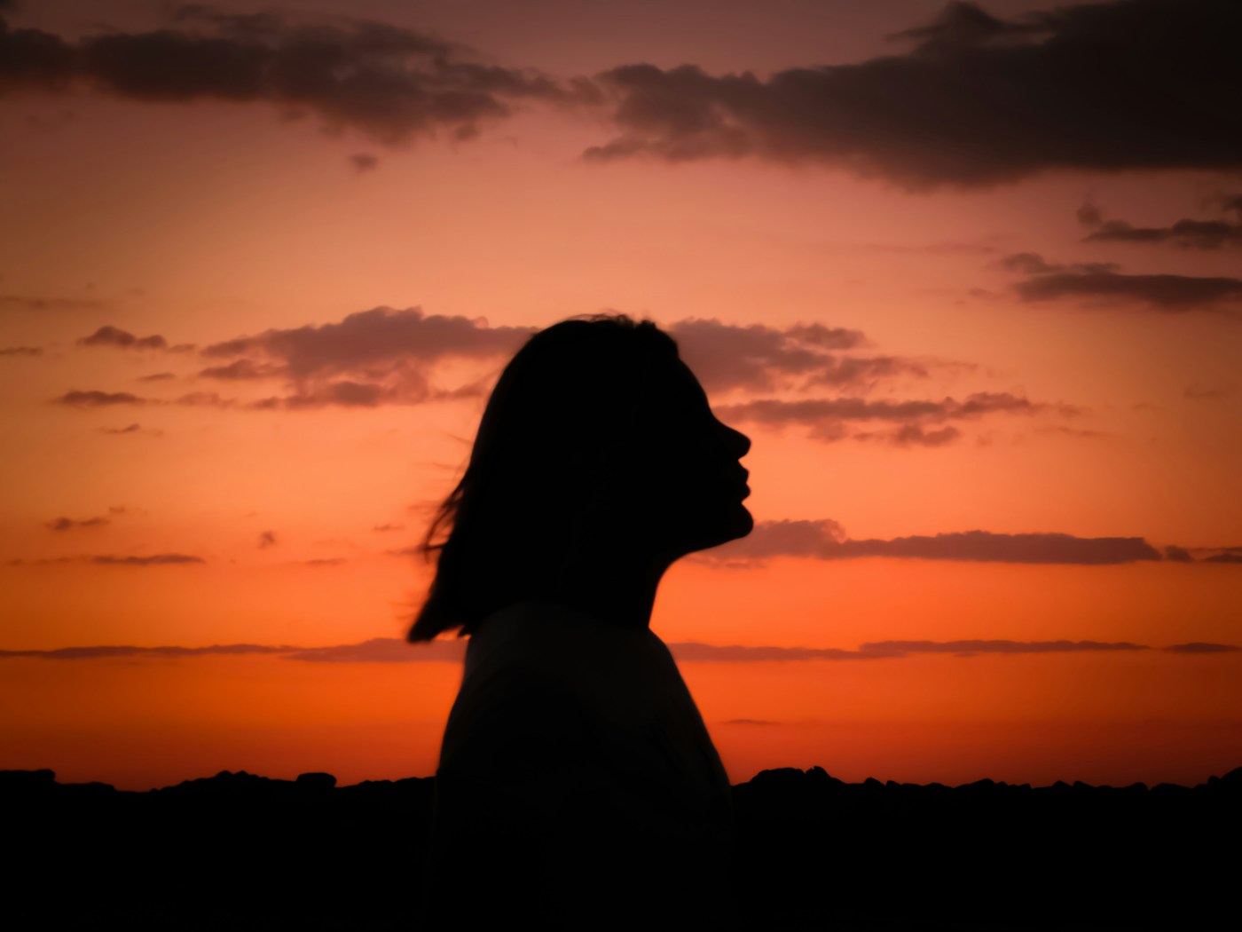 A woman in quiet reflection against a warm sunset sky